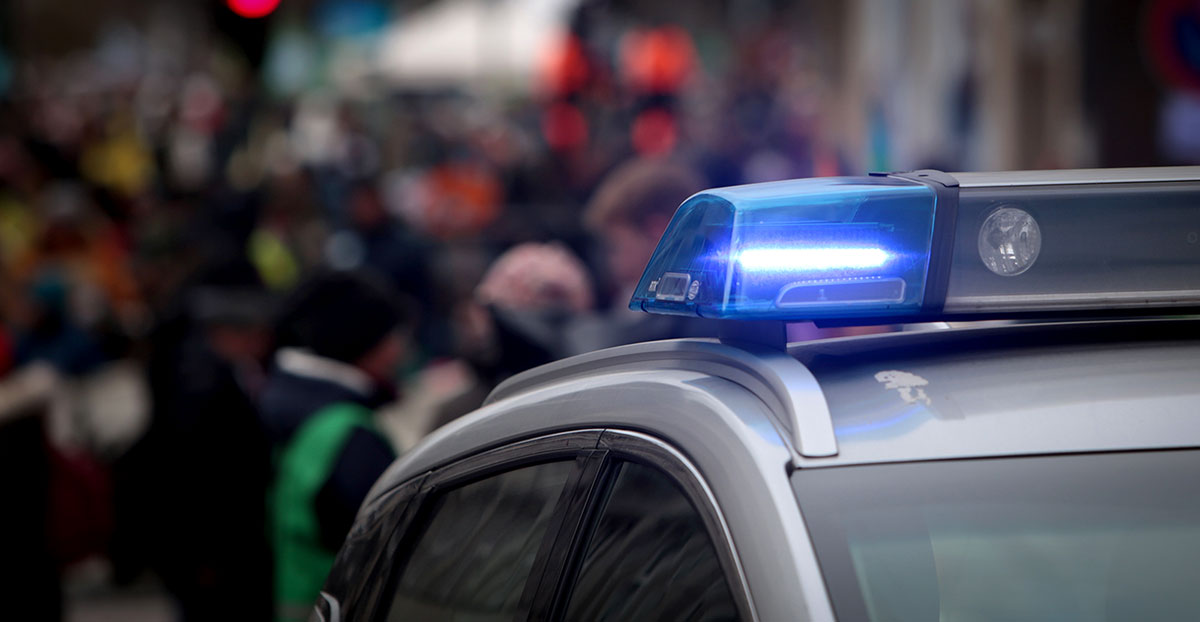 Police car light in front of a blurred crowd of people. 